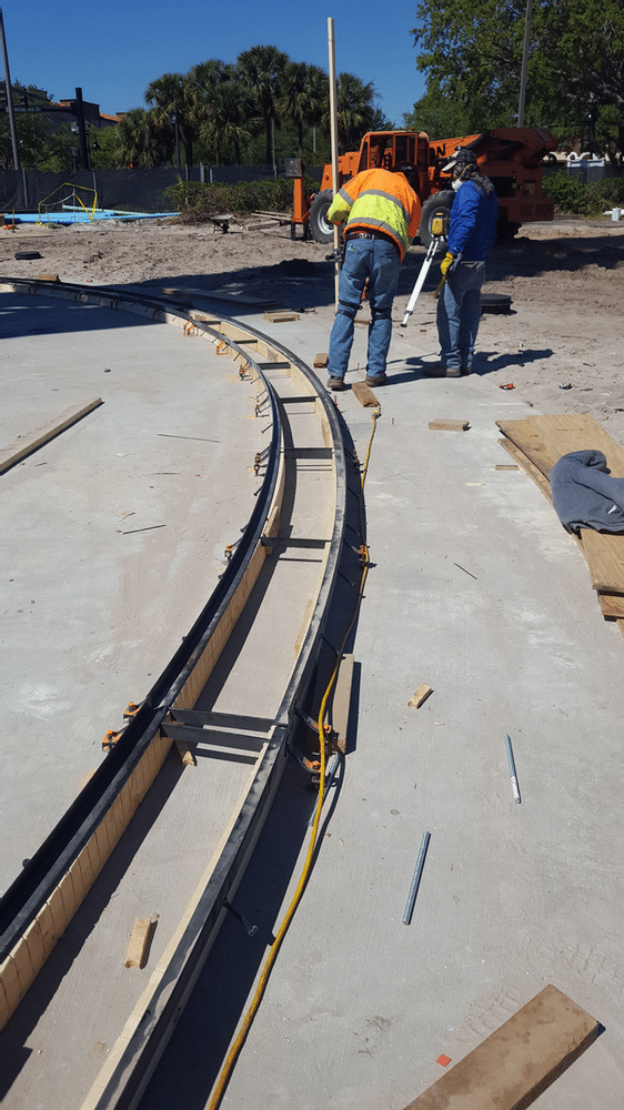 This contractor is hand forming a radius trench drain at the base of the Star Flier amusement park ride.